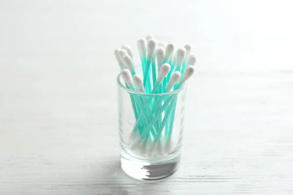 Glass with cotton swabs on white wooden background — Stock Photo, Image
