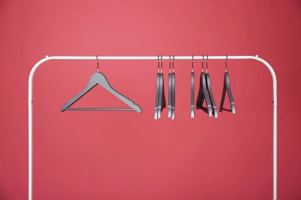 Appendiabiti vuoti su rack in metallo contro lo sfondo di colore — Foto Stock