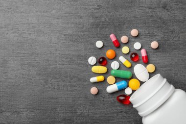 Gri arka planda farklı haplar ile Şişe, düz yatıyordu. Metin için alan