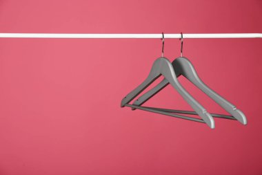 Renkli arka plana karşı metal rayüzerinde boş giysi askıları. Metin için alan