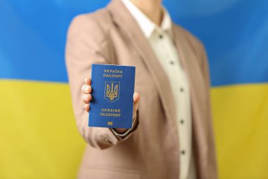 Ukrayna pasaportu taşıyan kadın ulusal bayrağa karşı, yakın plan. Uluslararası ilişkiler