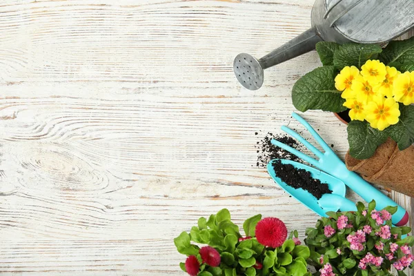 Composição de leigos planos com equipamentos de jardinagem e flores em fundo de madeira, espaço para texto — Fotografia de Stock