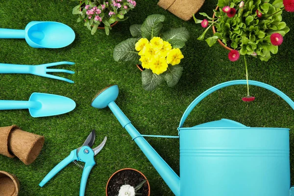 Composição de leigos plana com equipamento de jardinagem e flores na grama verde — Fotografia de Stock