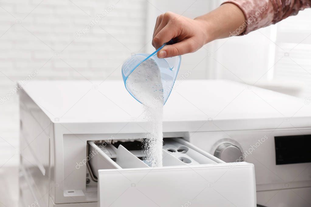 Woman pouring powder into drawer of washing machine indoors, closeup. Laundry day