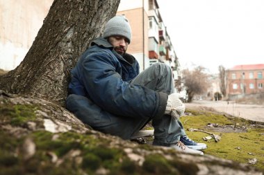 Zavallı evsiz adam dışarıda yerde oturuyor