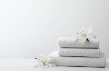 Beyaz arka plan karşı masada çiçek ile taze havlu Yığını. Metin için alan