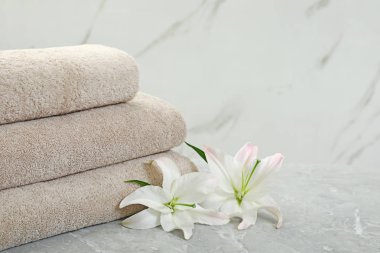 Açık arka plan karşı gri masa üzerinde çiçek ile taze havlu Yığını. Metin için alan