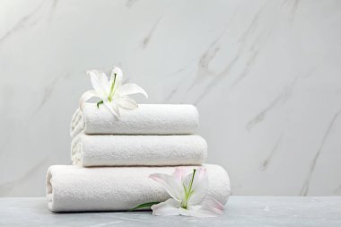 Açık arka plan karşı gri masa üzerinde çiçek ile taze havlu Yığını. Metin için alan