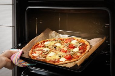 Lezzetli ev yapımı pizzayı fırından çıkaran kadın, yakın plan.