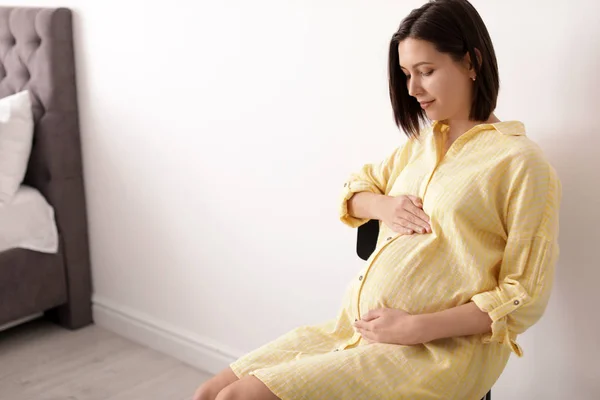 Mooie zwangere vrouw zittend in lichte kamer. Ruimte voor tekst — Stockfoto