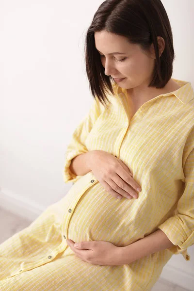 Piękna kobieta w ciąży siedzi w jasnym pomieszczeniu — Zdjęcie stockowe