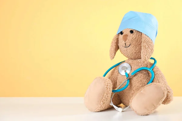 Toy Bunny med stetoskop på bordet mot färg bakgrund, utrymme för text. Barnens sjukhus — Stockfoto