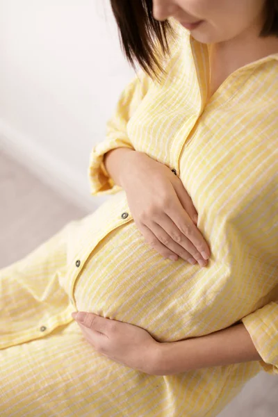 Красивая беременная женщина сидит в светлой комнате, крупным планом — стоковое фото