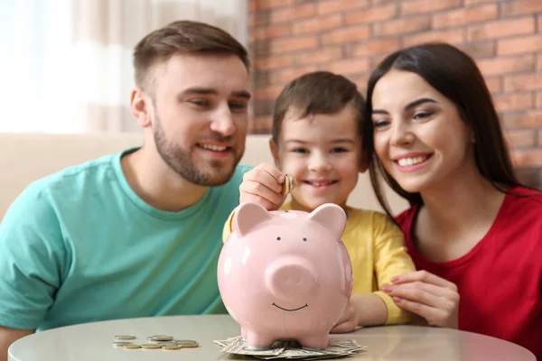 Familia feliz con alcancía y dinero en casa —  Fotos de Stock