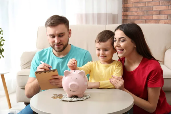 Gelukkige familie met Piggy Bank en geld thuis — Stockfoto