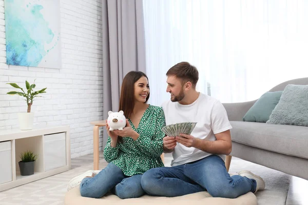 Beau jeune couple avec tirelire et argent à la maison — Photo