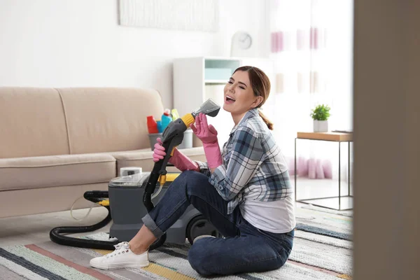 Gelukkig jonge vrouw schoonmaken huis met stofzuiger en plezier binnenshuis — Stockfoto
