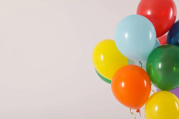 Stelletje heldere ballonnen op lichte achtergrond, ruimte voor tekst. Viering tijd — Stockfoto