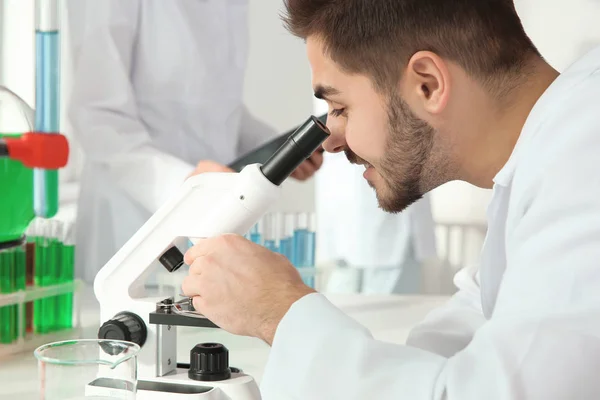 Student medicíny pracující s mikroskopem v moderní vědecké laboratoři — Stock fotografie