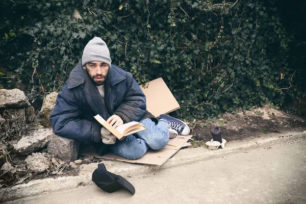 Homem pobre sem-teto com livro na rua na cidade — Fotografia de Stock