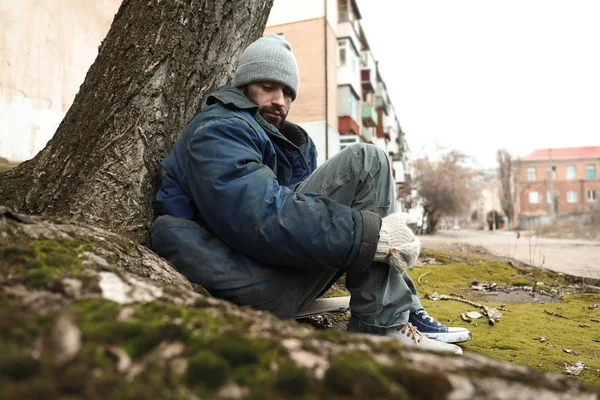 Stackars hemlösa man sitter på marken utomhus — Stockfoto