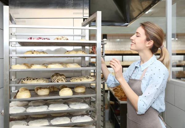 Baker at rack with pastries in workshop