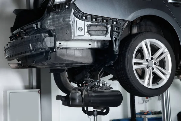 Carro moderno no elevador hidráulico na oficina de reparação de automóveis, close-up — Fotografia de Stock