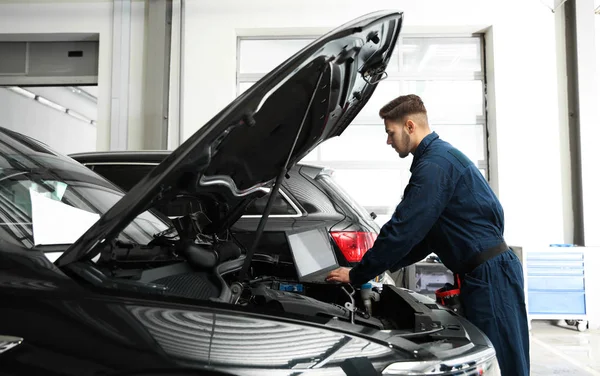 Técnico verificando carro com laptop na oficina de reparação de automóveis — Fotografia de Stock