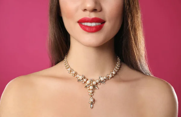 Mulher bonita com jóias elegantes no fundo de cor, close-up — Fotografia de Stock