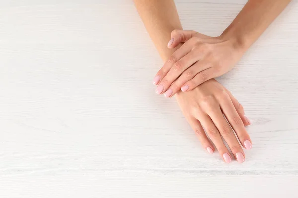 Vista de close-up da mulher com belas mãos na mesa de madeira branca, espaço para texto. Tratamento de Spa — Fotografia de Stock