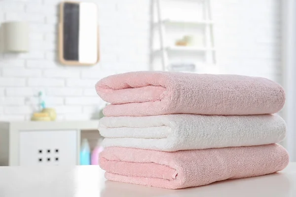 Stack of fresh towels on table in bathroom. Space for text — Stock Photo, Image