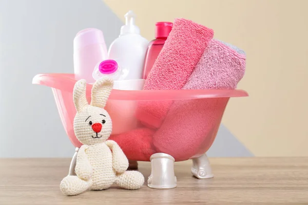 Baby cosmetische producten, gebreid konijn en handdoeken op tafel tegen kleur achtergrond — Stockfoto
