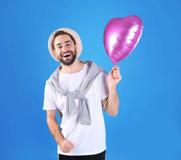 Portrait de jeune homme avec ballon en forme de coeur sur fond de couleur — Photo