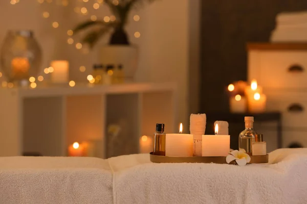 Cosméticos e velas acesas na mesa de massagem no salão de spa, espaço para texto — Fotografia de Stock