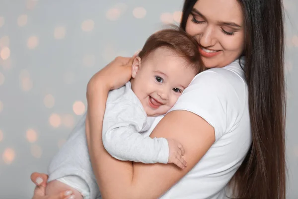 Porträtt av ung mor och hennes bedårande baby mot defokuserad Lights — Stockfoto