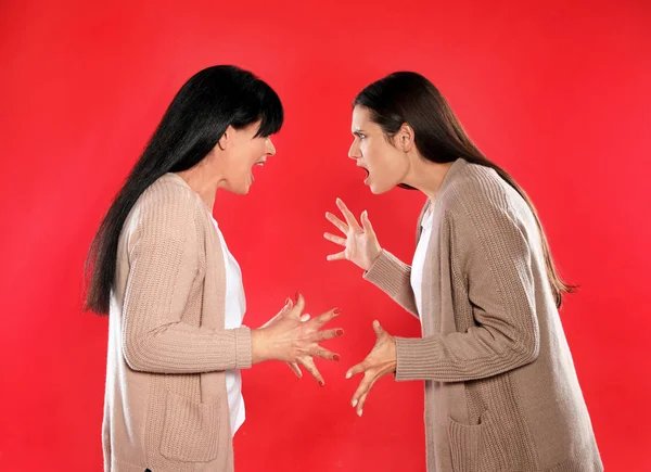 Hija joven y su madre madura discutiendo sobre el fondo de color — Foto de Stock