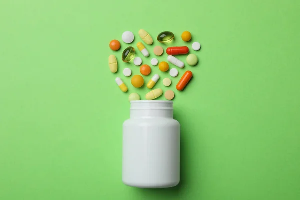 Garrafa com diferentes pílulas em fundo de cor, flat lay — Fotografia de Stock