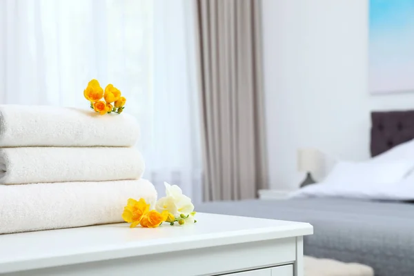 Pilha de toalhas frescas com flores no armário no quarto. Espaço para texto — Fotografia de Stock
