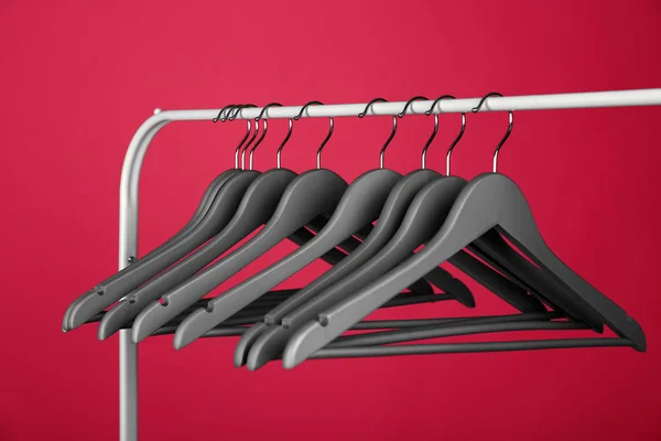 Empty clothes hangers on metal rack against color background — Stock Photo, Image