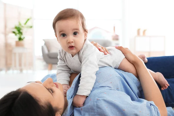 Feliz joven madre jugando con el bebé en el suelo en casa — Foto de Stock