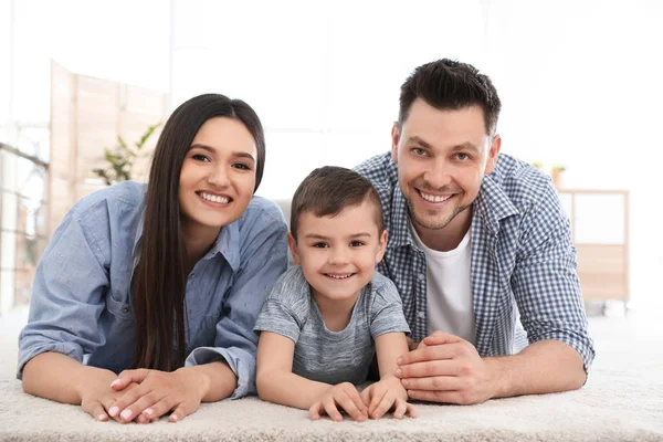 Pareja feliz y su hijo tumbados en la alfombra en casa. Tiempo en familia — Foto de Stock