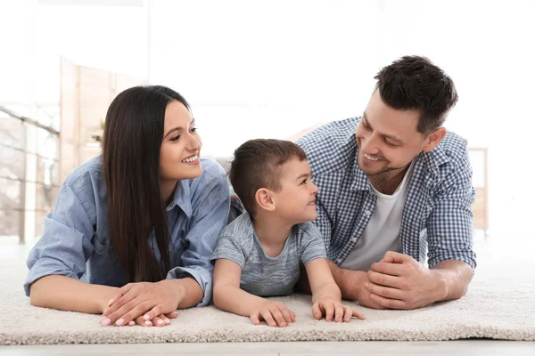Gelukkig paar en hun zoon liggend op tapijt thuis. Family time — Stockfoto