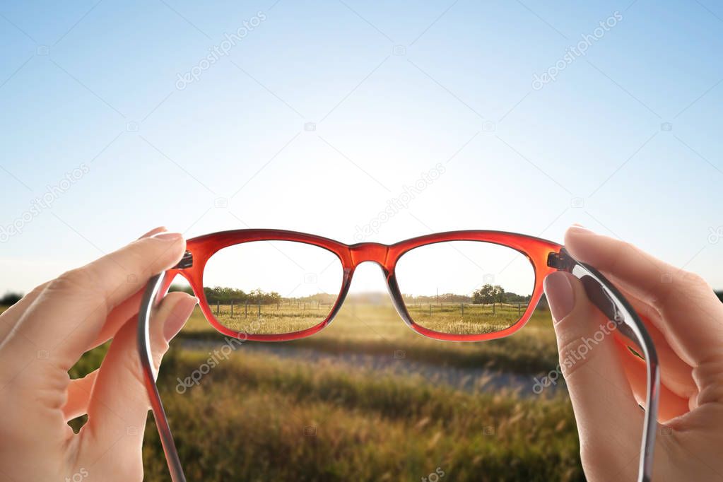 Woman looking through glasses, closeup. Improvement of vision after visiting ophthalmologist