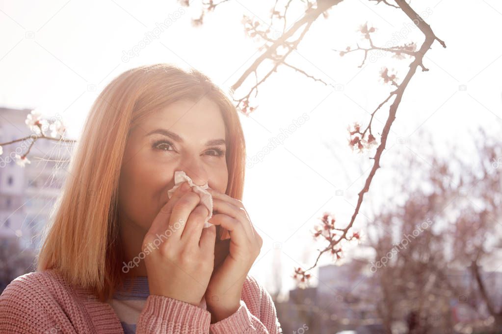 Woman suffering from seasonal allergy outdoors, space for text