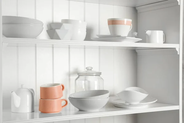 Stijlvolle opbergstand met verschillende keramische servies thuis — Stockfoto