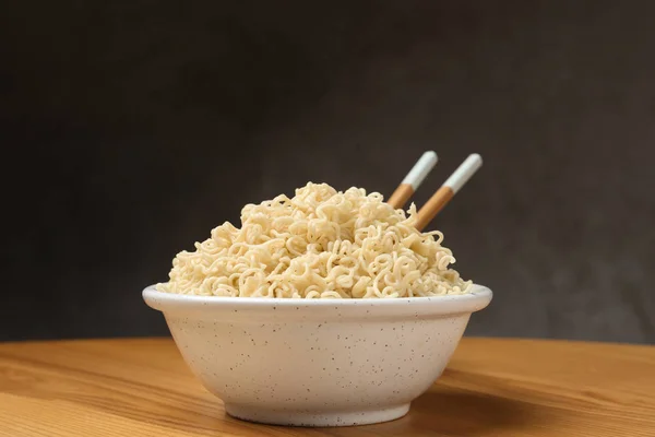 Tigela de macarrão quente com pauzinhos na mesa contra fundo cinza — Fotografia de Stock