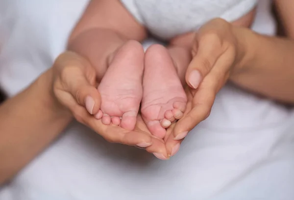 Matka drží nohy její roztomilé miminko v rukou, closeup — Stock fotografie