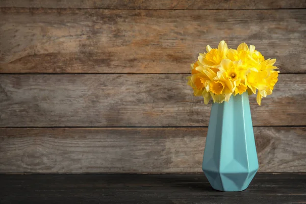 Ramillete de narcisos en jarrón sobre mesa sobre fondo de madera, espacio para texto. Flores frescas de primavera — Foto de Stock