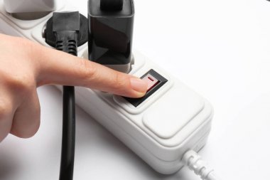 Beyaz arka planda uzatma kablosunun güç düğmesine basarak kadın, çekim. Elektrikçi profesyonel ekipmanları