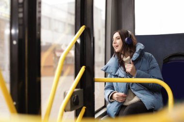 Genç kadın toplu taşıma kulaklıklar ile müzik dinleme